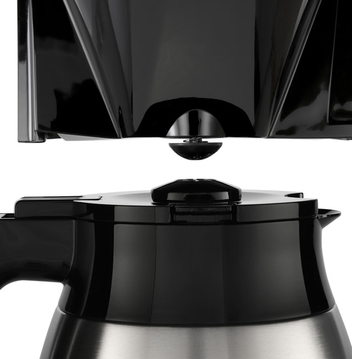 Nahaufnahme eines schwarzen Kaffeemaschinenteils mit Edelstahlbasis und Deckel