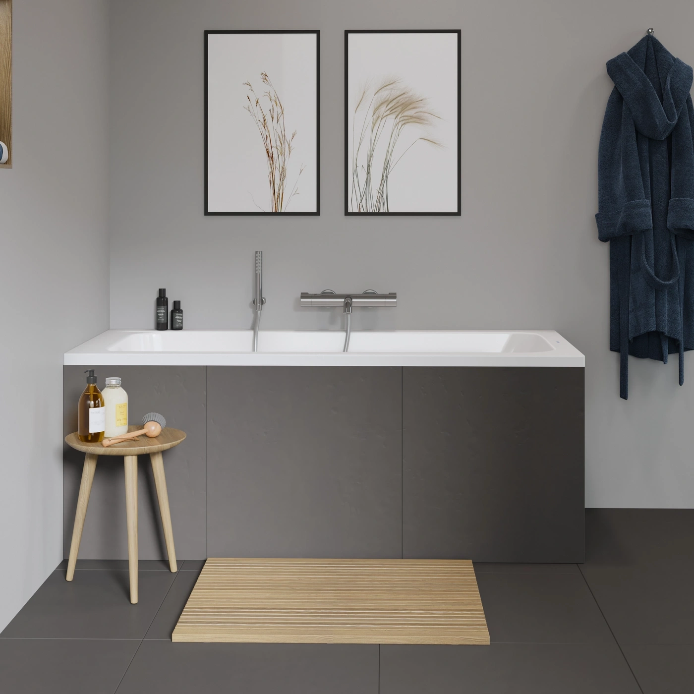 Badezimmer mit Badewanne, Badematte, Bildern und Bademantel an der Wand.