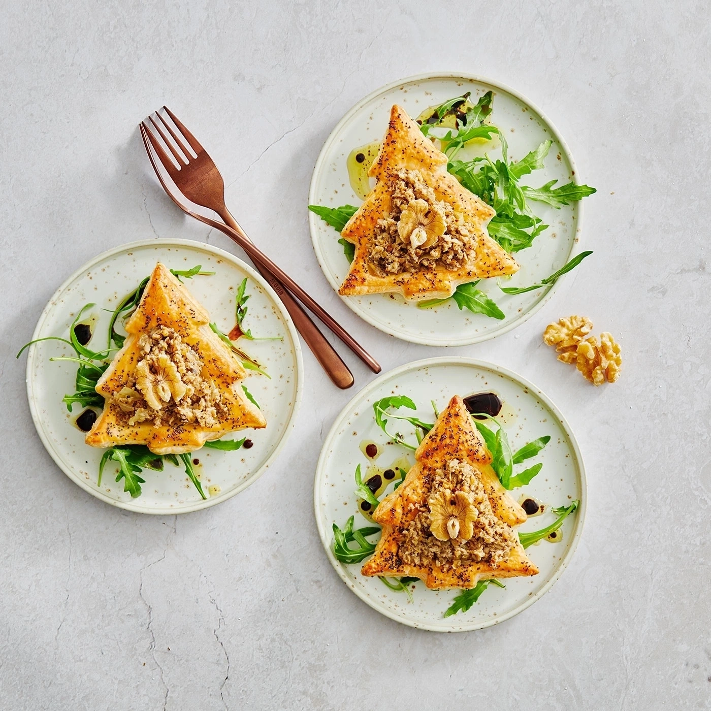 Weihnachtsbaum-Gebäck auf Tellern mit Walnüssen und Rucola, köstlich angerichtet.