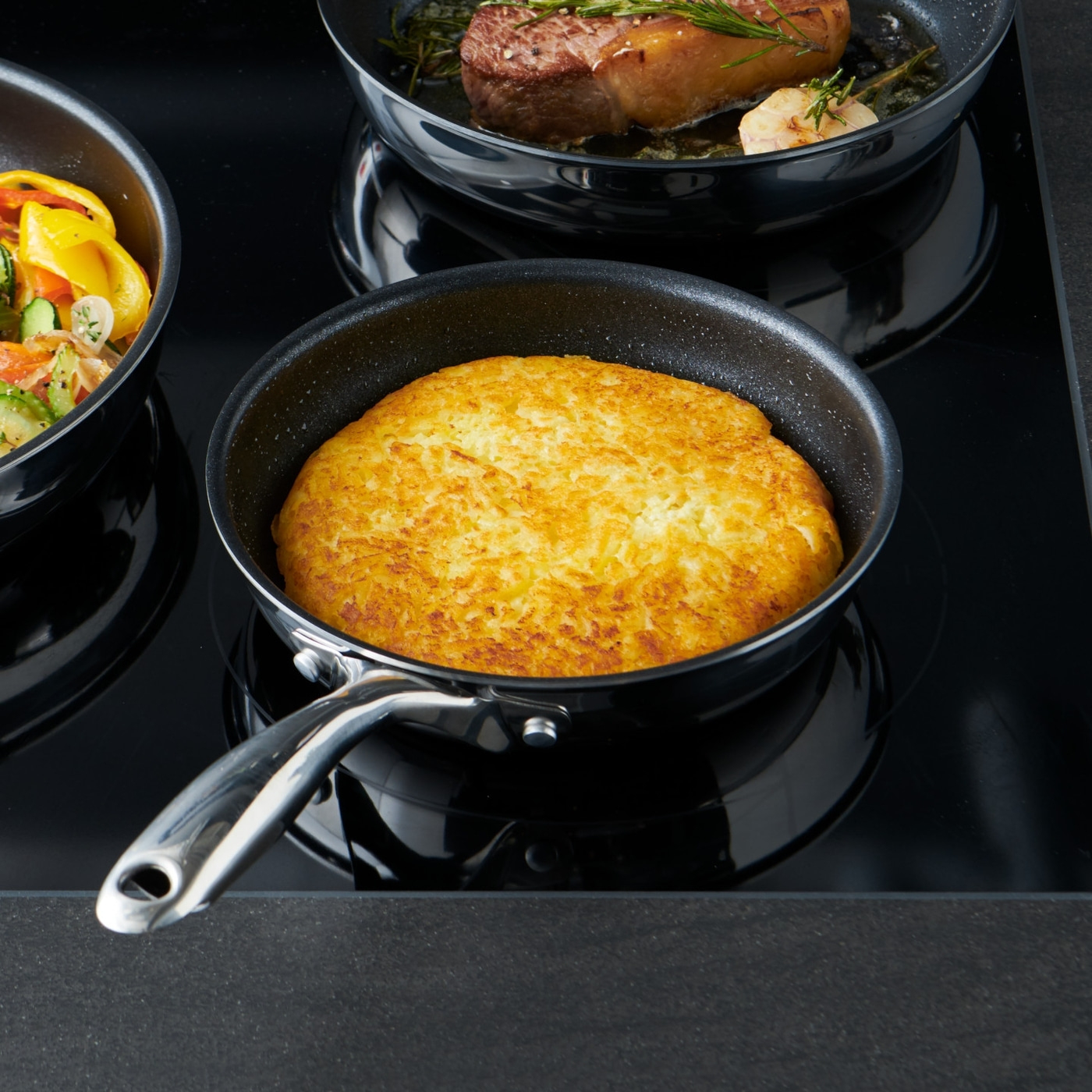 Pfanne mit Bratkartoffeln, Steak und Gemüse auf Herdplatte