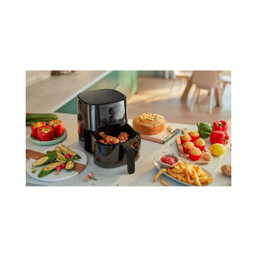 Luftfritteuse mit Essen, Gemüse und Kuchen auf einem Tisch