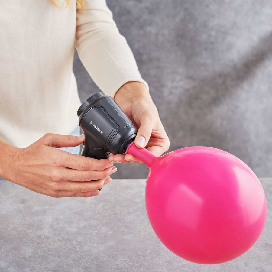 Person bläst einen rosa Ballon mit einer schwarzen Pumpe auf. Betty Bossi.