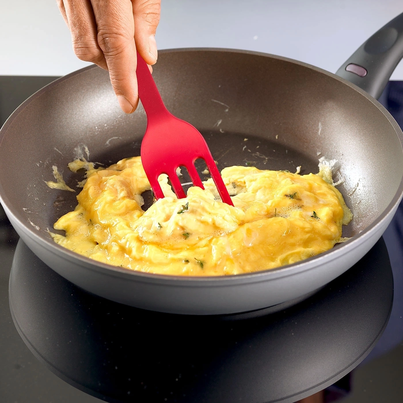 Rührei wird in einer Pfanne mit roter Gabel zubereitet.