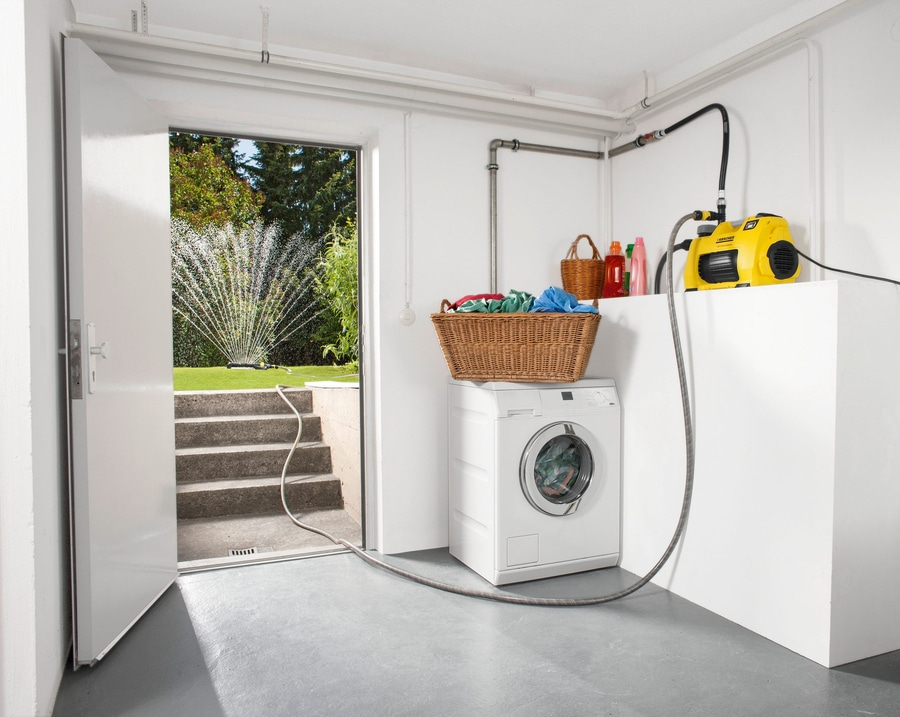 Waschküche mit Waschmaschine, Korb, Tür, Rasensprenger und gelber Pumpe