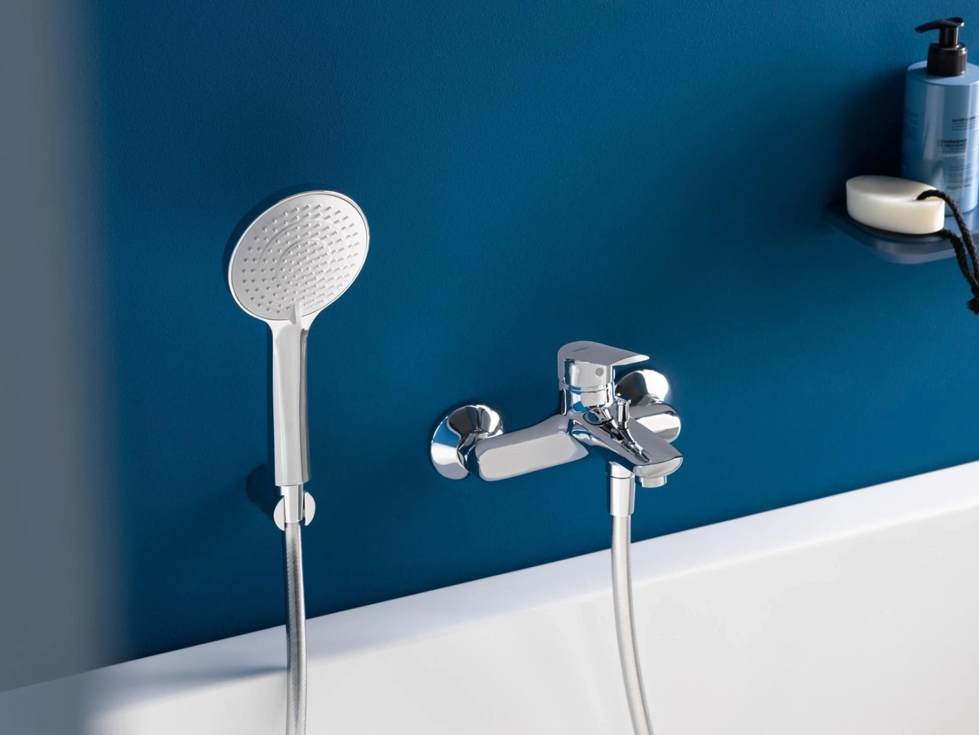 Chrom-Duscharmatur und Handbrause vor blauer Wand in einem Badezimmer