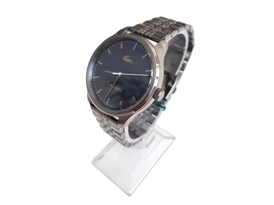 Eine schwarze Lacoste-Armbanduhr mit silbernem Armband auf einem Ständer