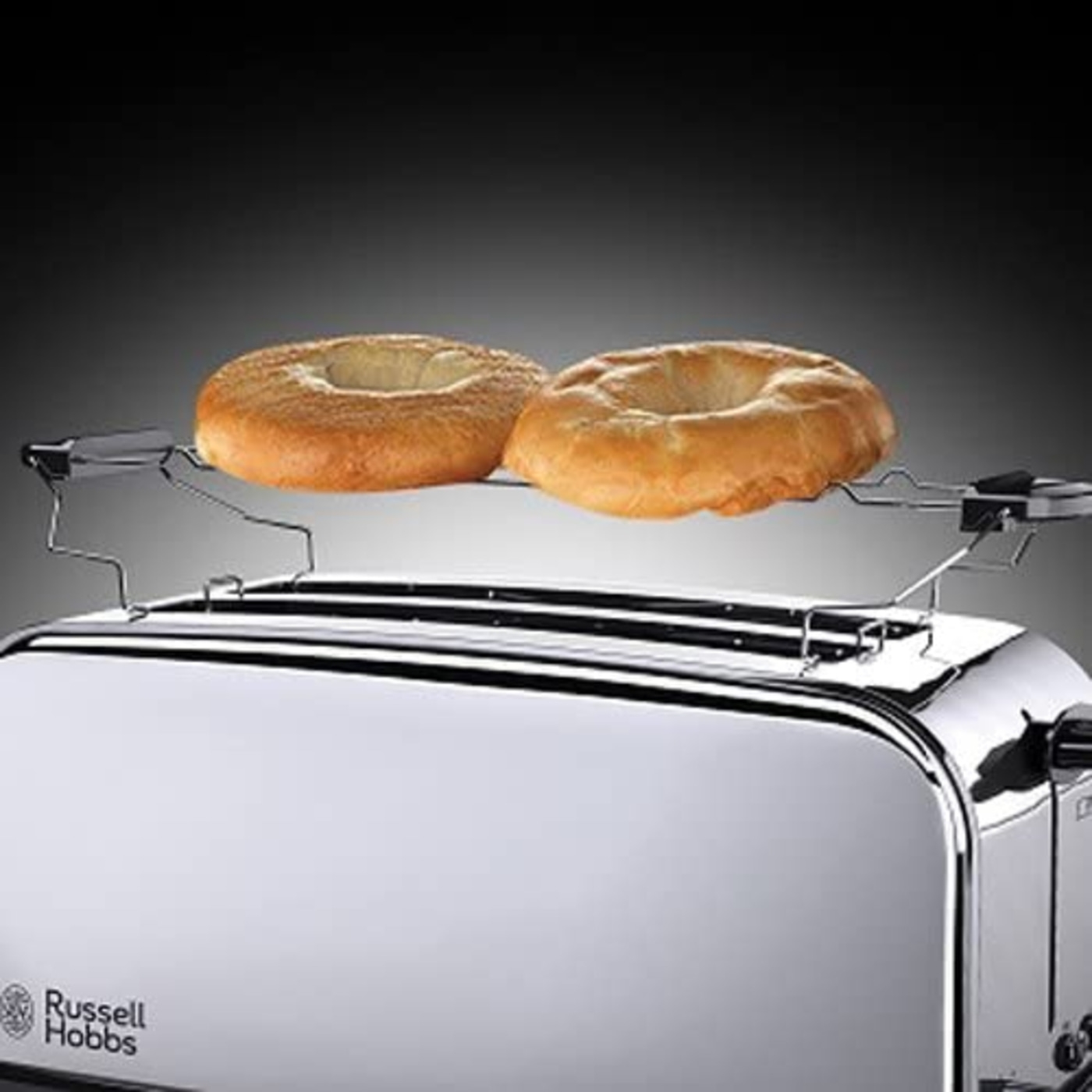 Ein Toaster mit zwei Bagels, die darauf liegen, vor einem dunklen Hintergrund.