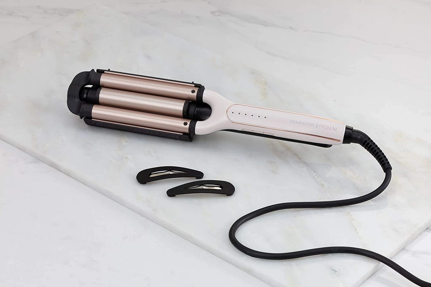 Haarstyling-Gerät mit zwei Haarspangen auf einer Marmorplatte. Remington Proluxe.