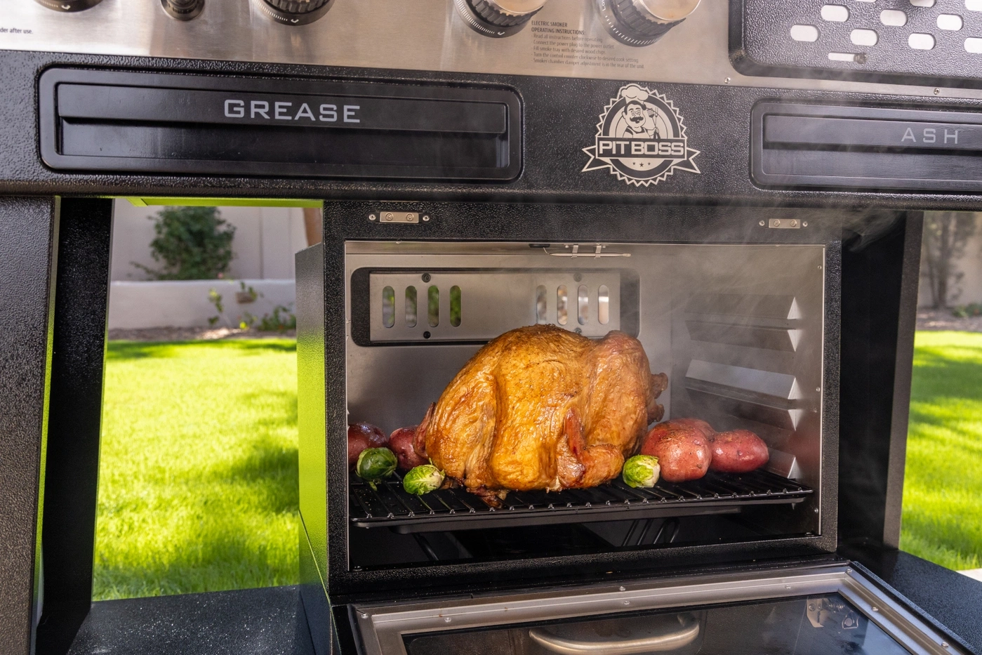 Ein goldbrauner Truthahn wird in einem Pit Boss Smoker mit Kartoffeln und Rosenkohl gegrillt.