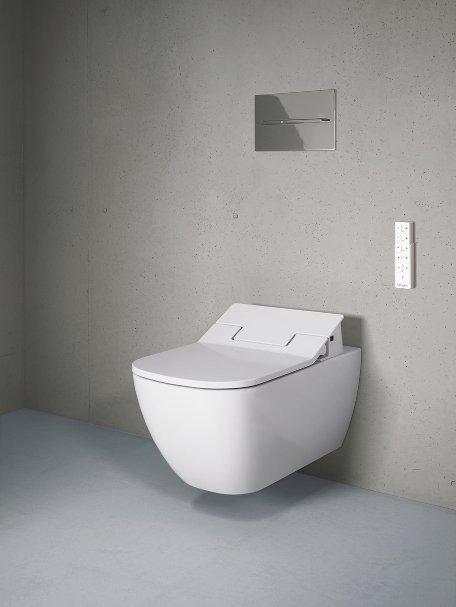 Weißes, modernes WC mit Fernbedienung an einer Betonwand in einem Badezimmer
