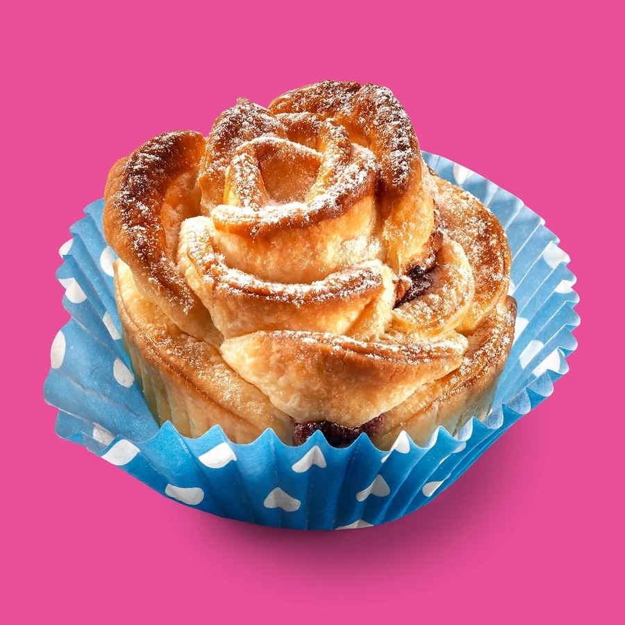 Gebäck in einer blauen Papierform mit rosa Hintergrund und Puderzucker
