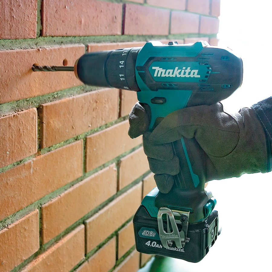 Makita-Bohrmaschine bohrt in eine Ziegelmauer, Nahaufnahme, Handwerker, Werkzeug