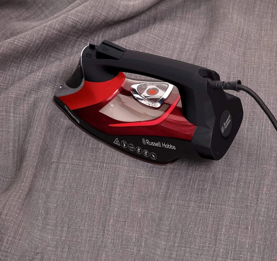 Bügeleisen auf grauem Stoff. Rot-schwarzes Bügeleisen von Russell Hobbs. Bügeln.