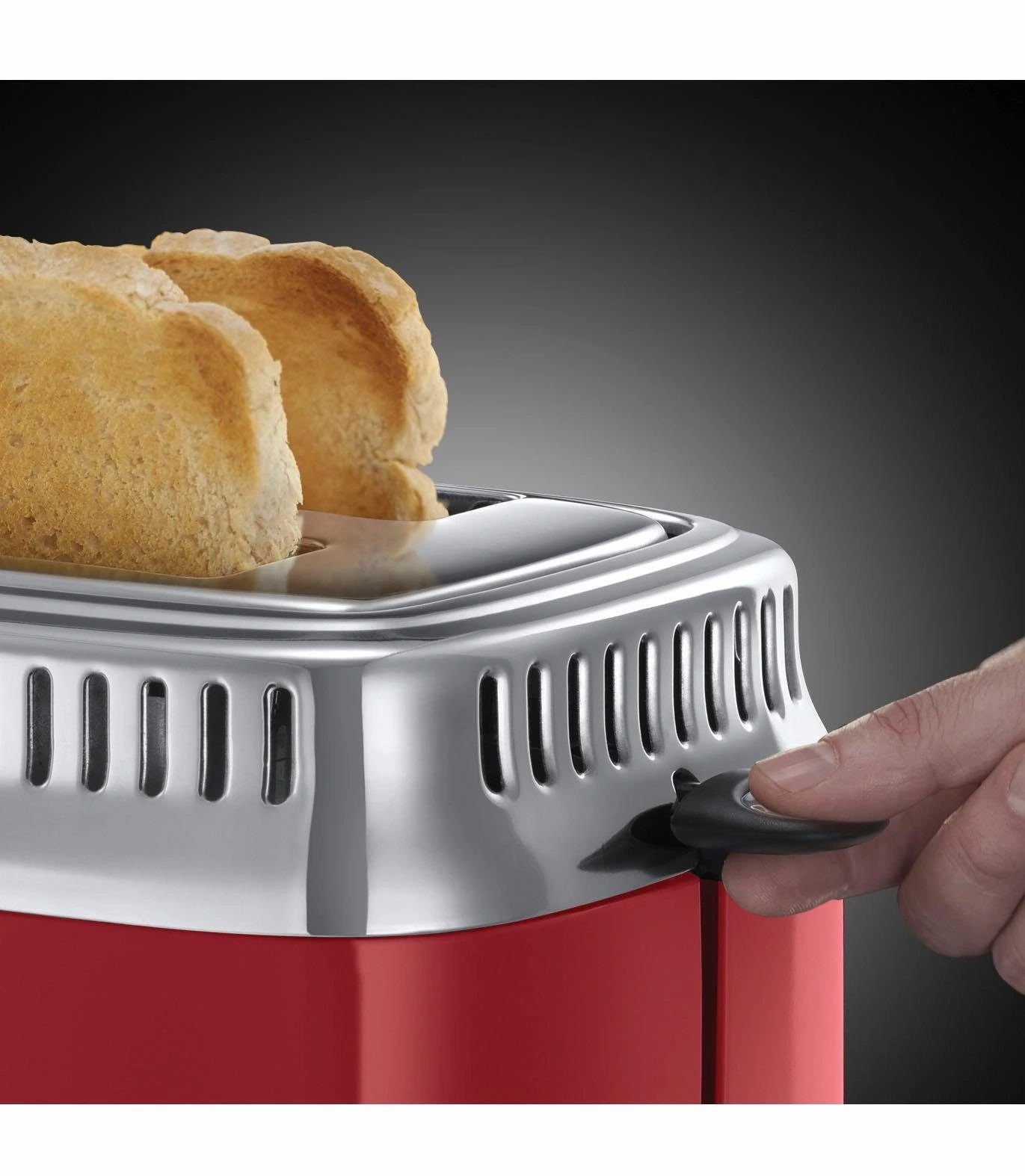 Nahaufnahme eines Toasters mit Toastbrot, das herausspringt, und einer Hand, die einen Hebel betätigt.