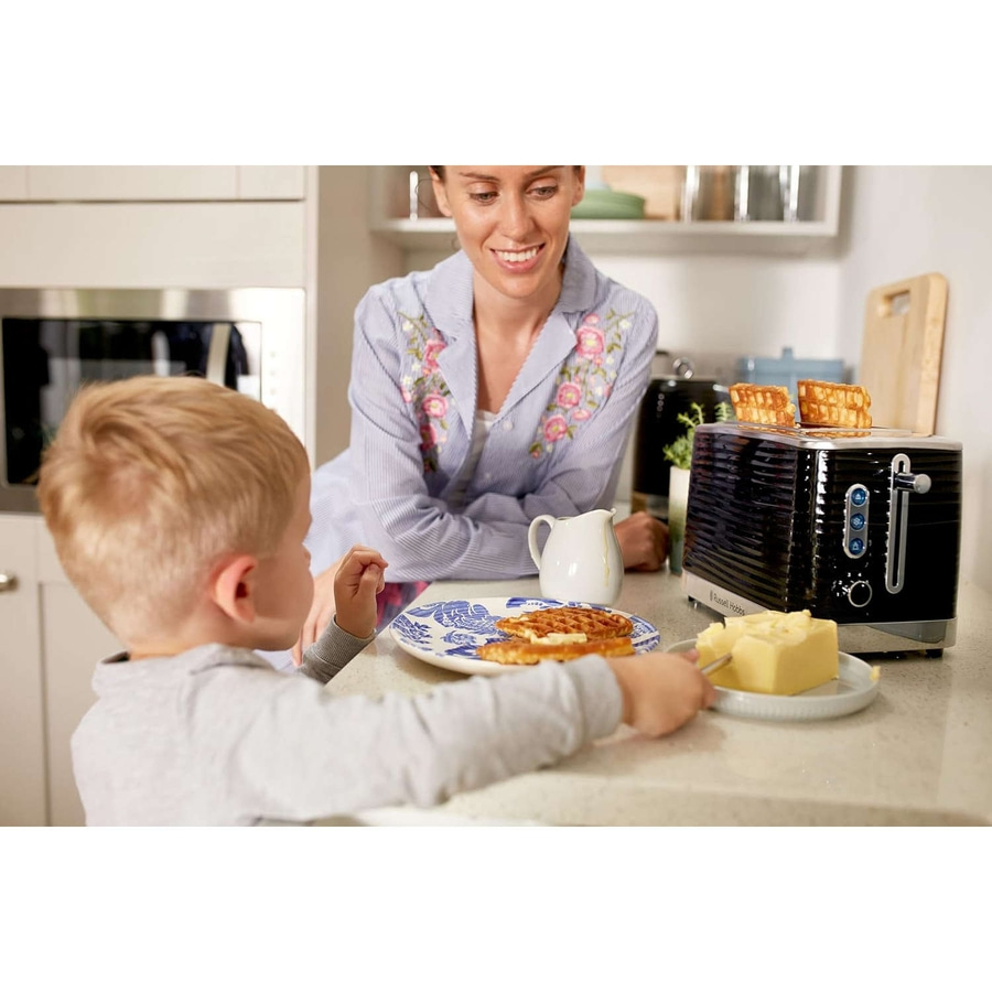 Mutter und Kind beim Frühstück mit Toast und Butter in der Küche