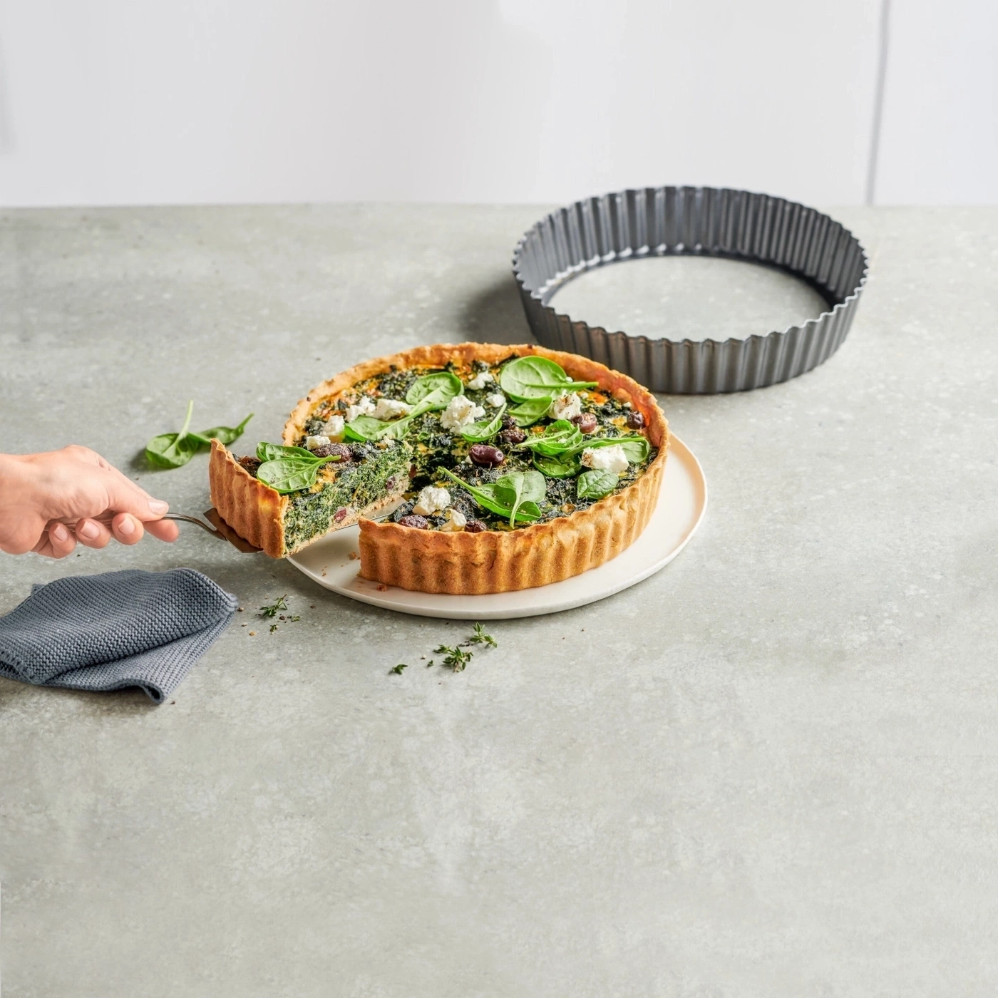 Köstliche Quiche mit Spinat, Käse und Oliven auf einem Teller