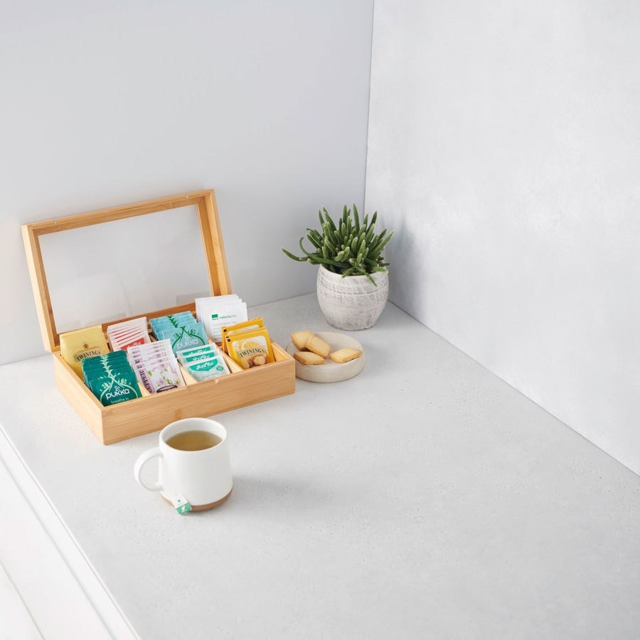 Tee-Set mit Tasse, Teebeuteln und Keksen auf weißer Oberfläche