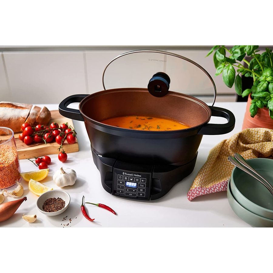 Kochtopf mit Suppe, Gemüse und Zutaten auf einem Tisch