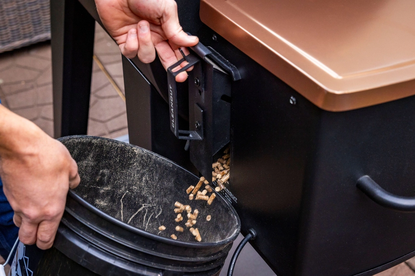 Holzpellets werden aus einem Grill in einen Eimer geschüttet.