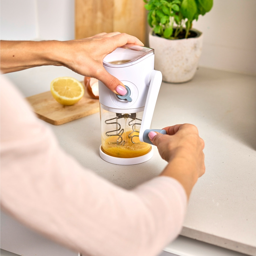 Person benutzt Küchengerät, um Eier zu verquirlen, mit Zitrone im Hintergrund.