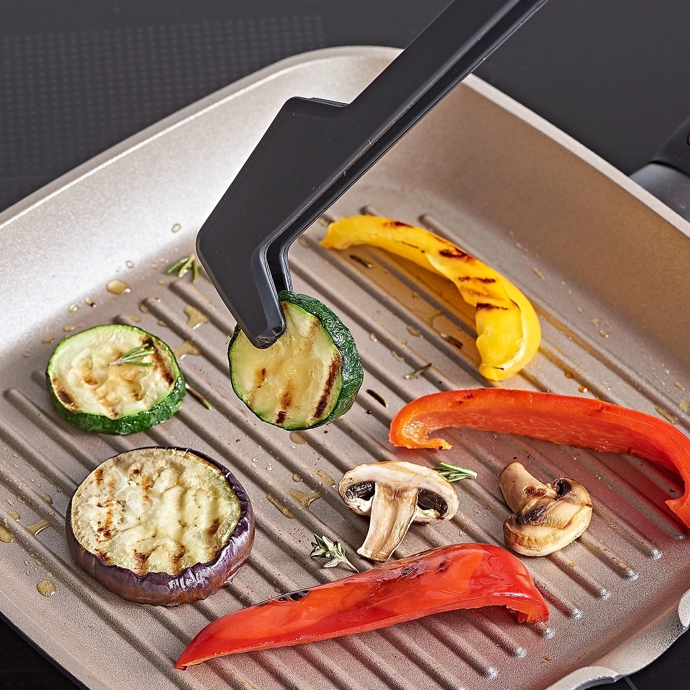 Gebratene Gemüse auf Grillpfanne mit Zange. Zucchini, Paprika, Aubergine und Pilze.