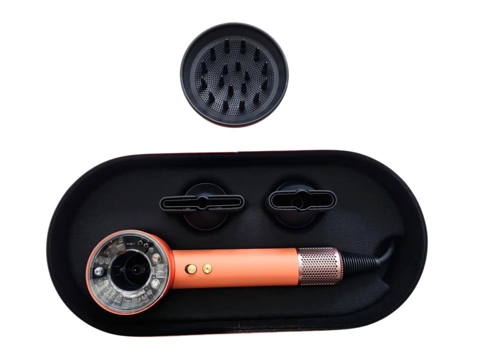 Ein orangefarbener Haartrockner mit Zubehör in einem schwarzen Etui