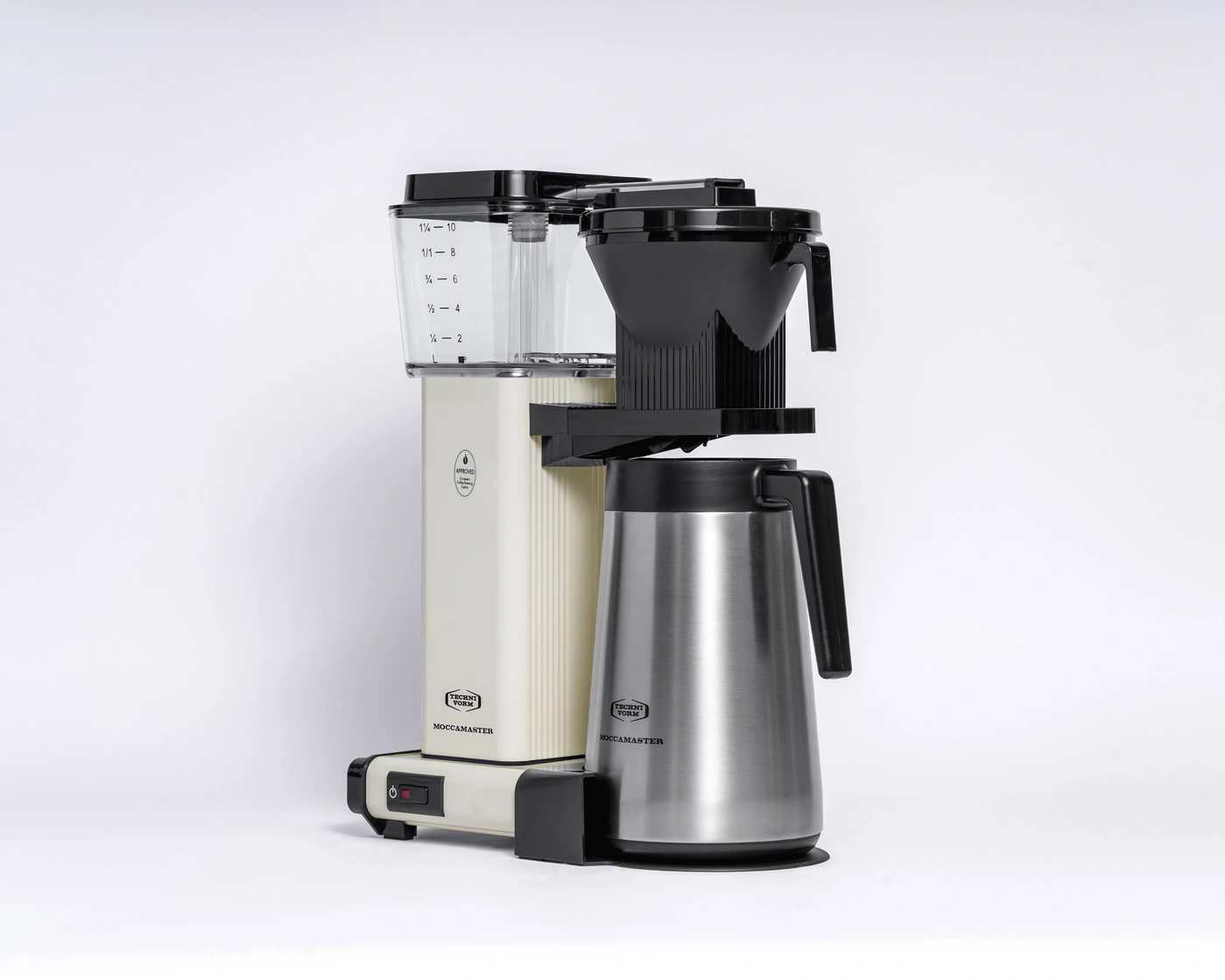 Eine cremefarbene Moccamaster Kaffeemaschine mit silberner Thermoskanne steht vor einem weißen Hintergrund.