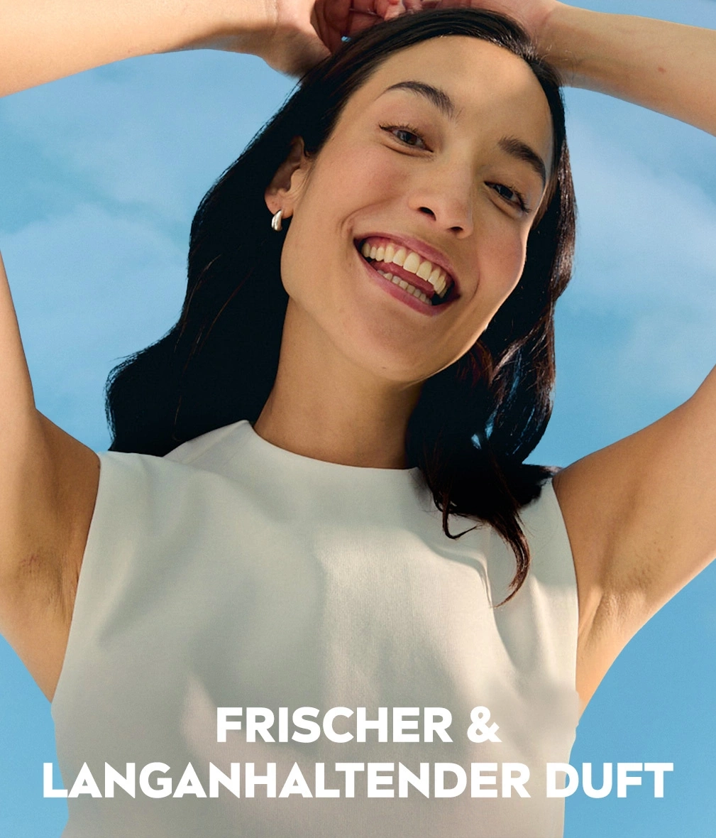 Frau mit erhobenen Armen lacht vor blauem Himmel