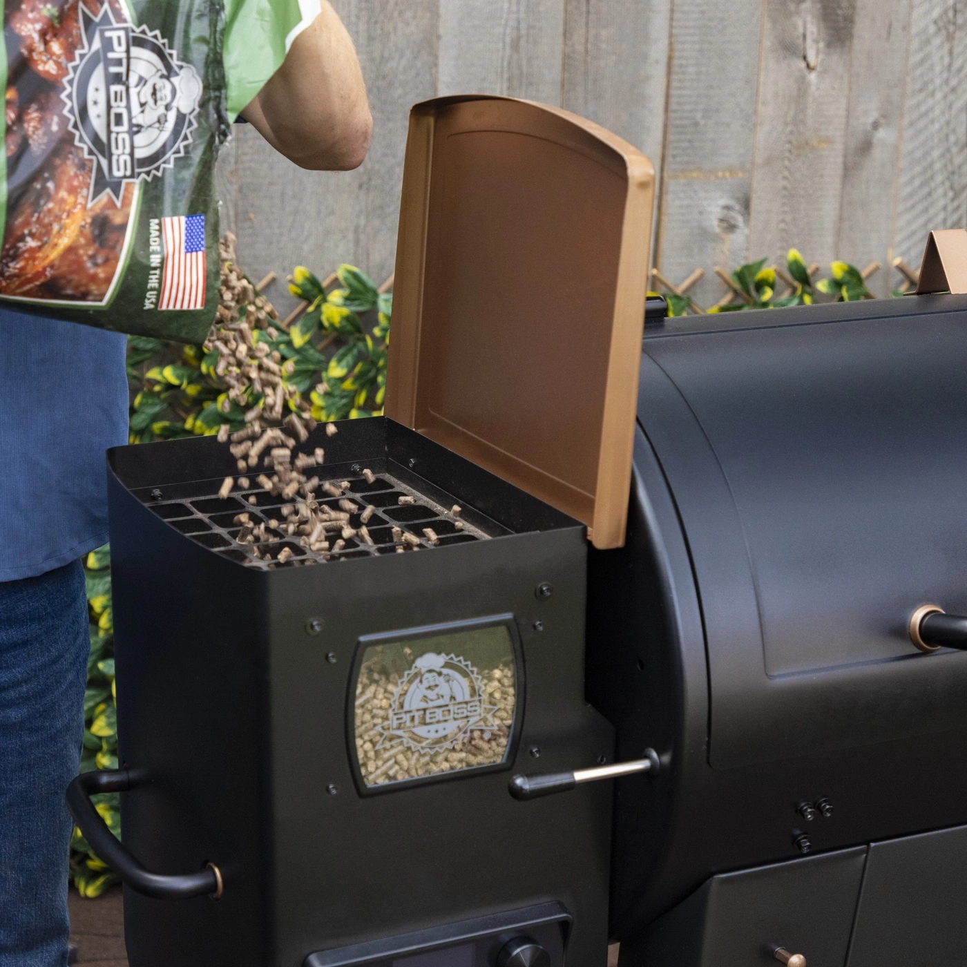 Mann schüttet Holzpellets aus einer Tüte in einen Grill.