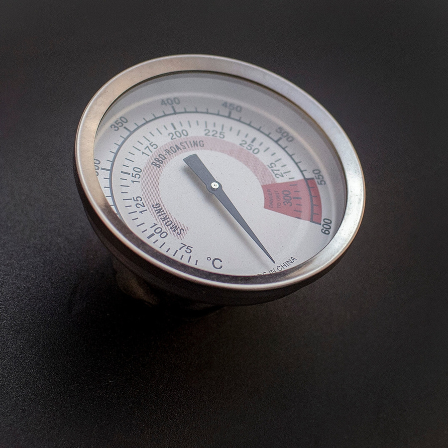 Nahaufnahme eines Thermometers, das die Temperatur anzeigt, mit den Wörtern 'SMOKING' und 'DANGER TO UNIT'.