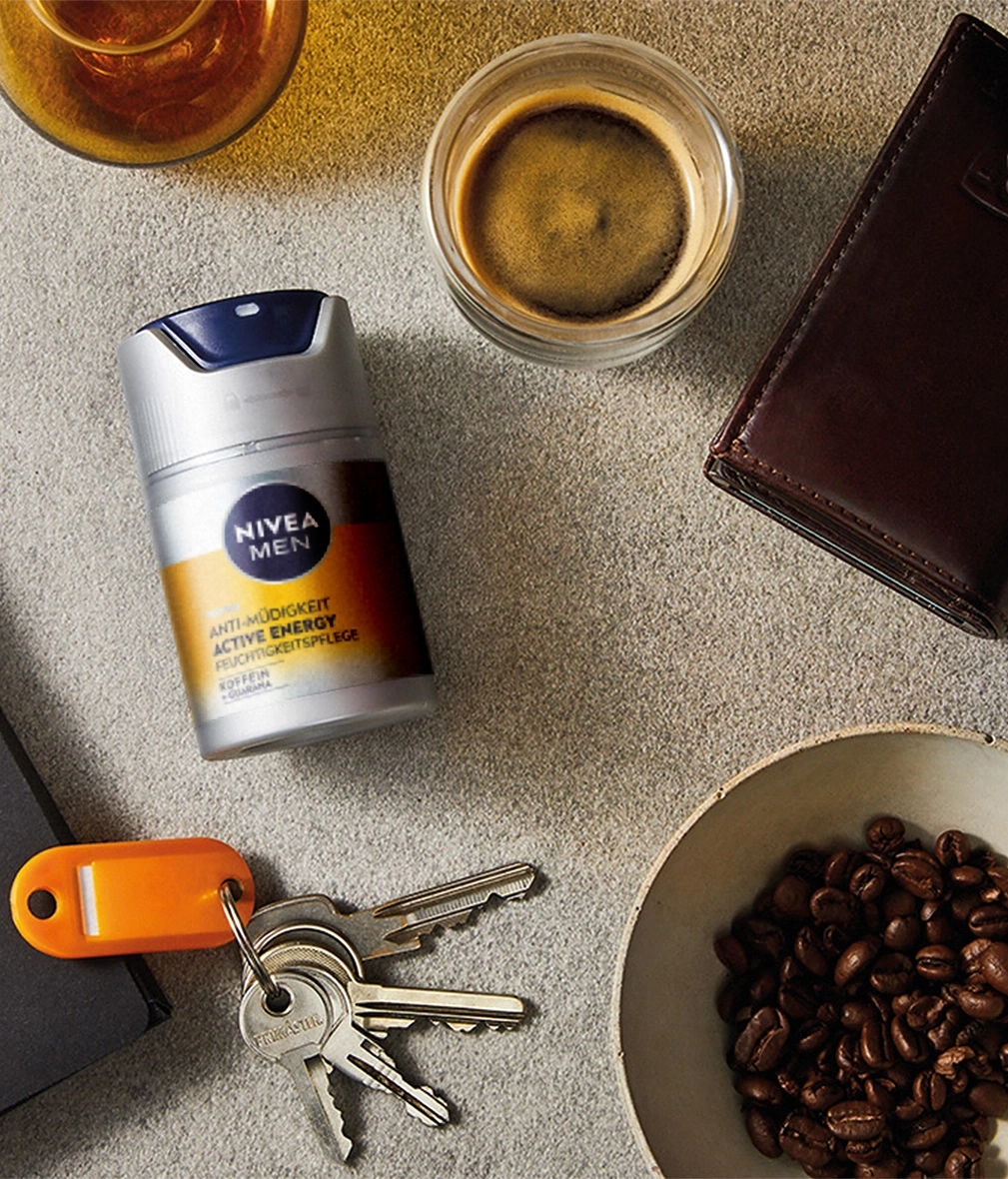 Nivea Men Produkt, Kaffee, Schlüssel, Geldbörse, Kaffeebohnen, Getränke auf grauem Hintergrund