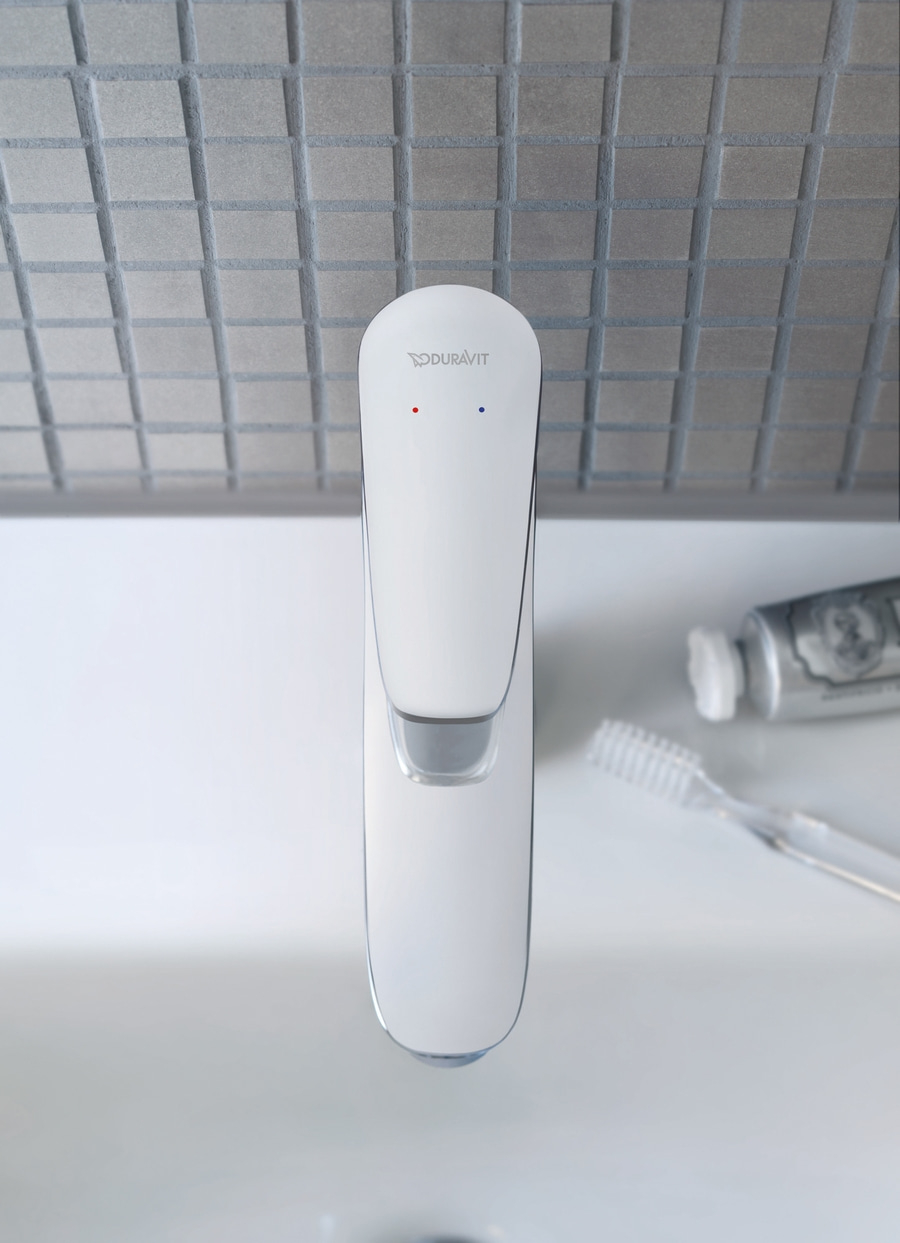 Weißer Wasserhahn mit Zahnbürste und Zahnpasta im Badezimmer, Nahaufnahme.