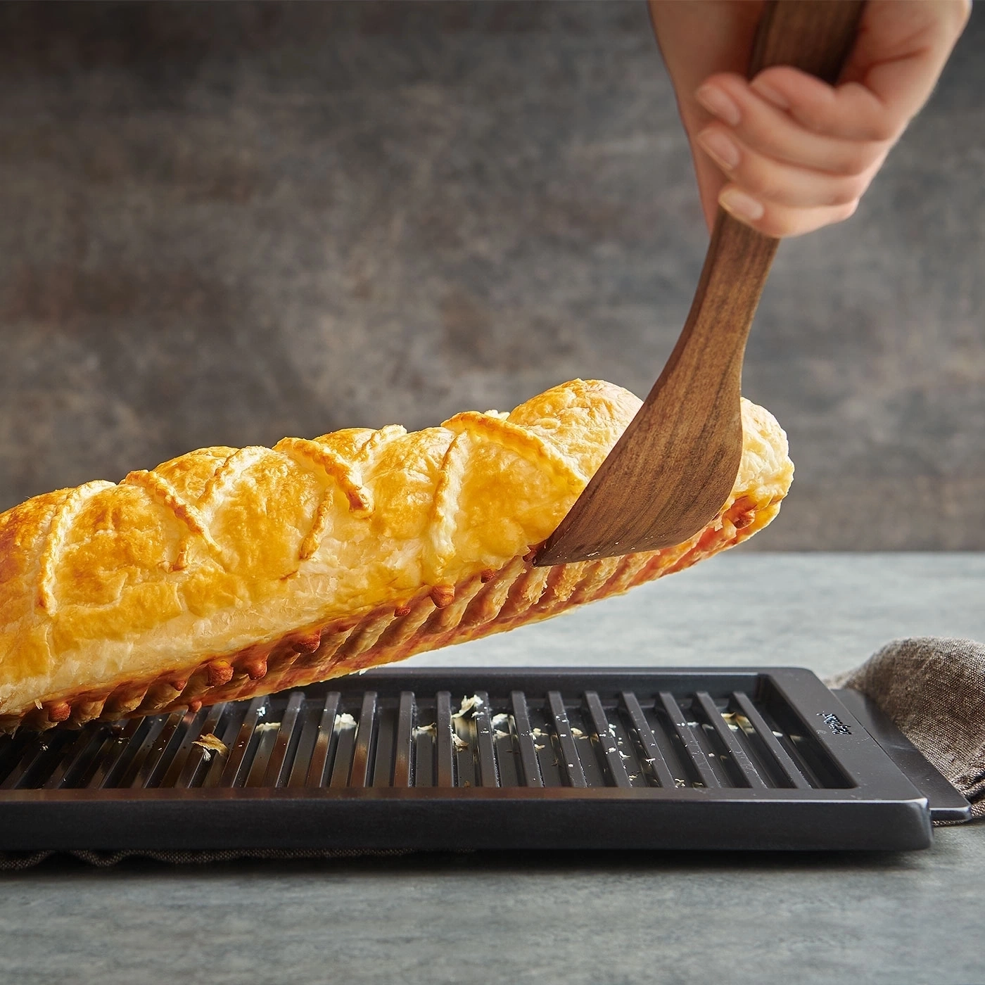 Ein köstliches Gebäck wird mit einem Holzspatel von einem Grill gehoben.