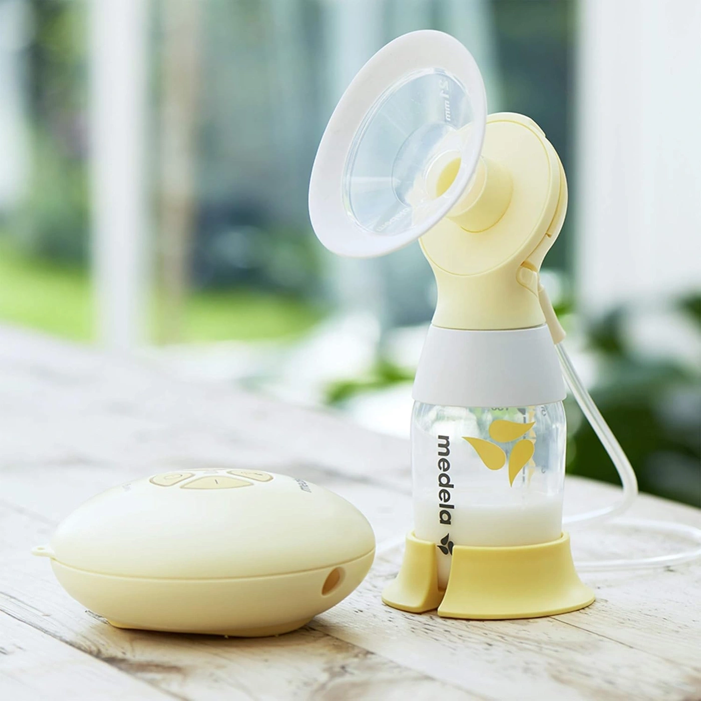 Elektrische Milchpumpe mit Flasche und Gerät auf Holzoberfläche, Nahaufnahme