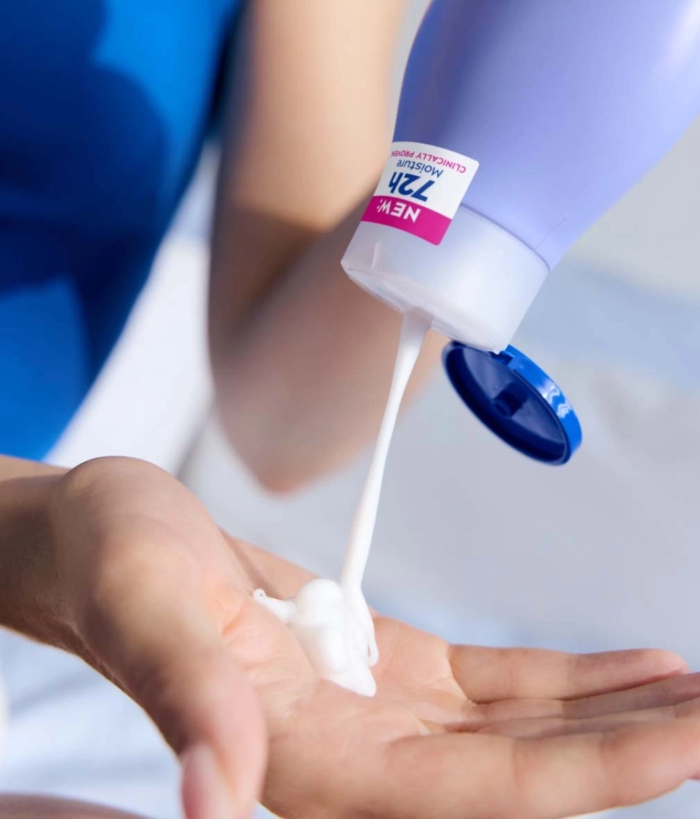 Person gießt Creme aus einer Flasche in ihre Handfläche, Nahaufnahme.