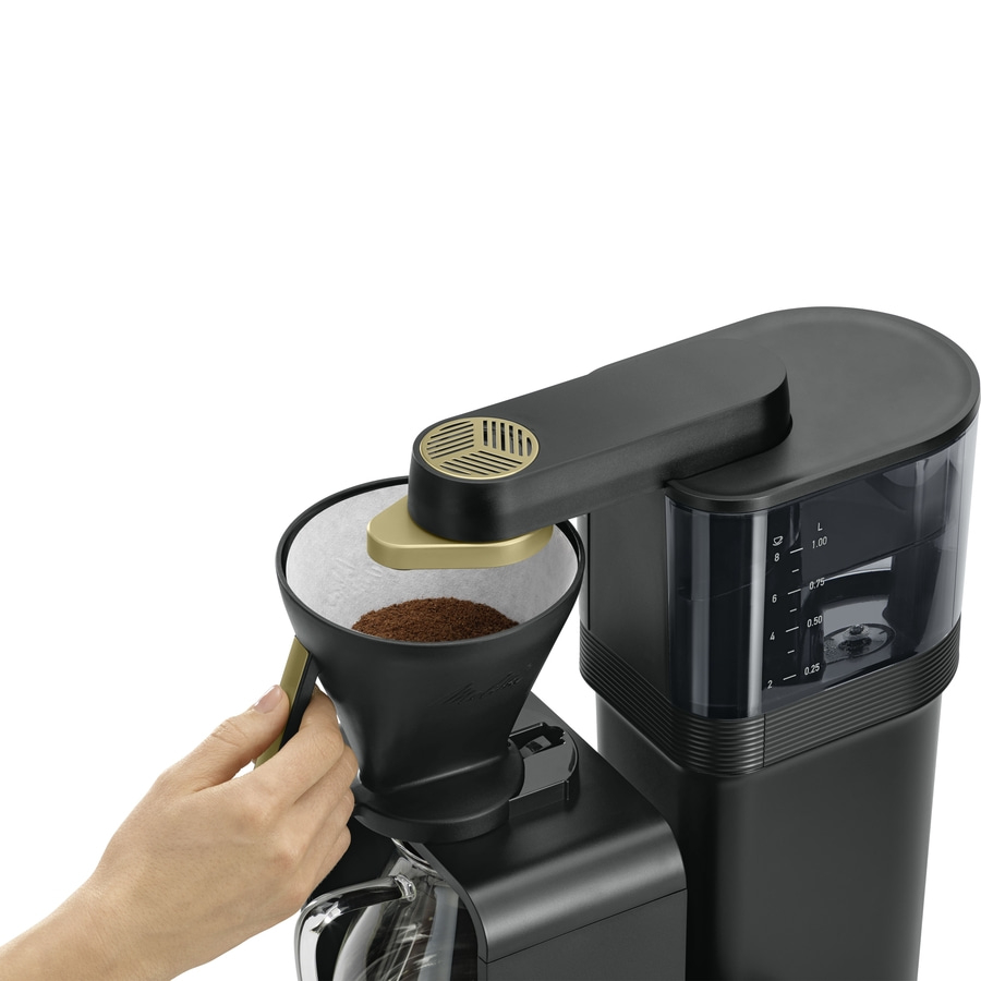 Kaffeemaschine mit Kaffeefilter und Kaffeepulver, Hand hält Filter