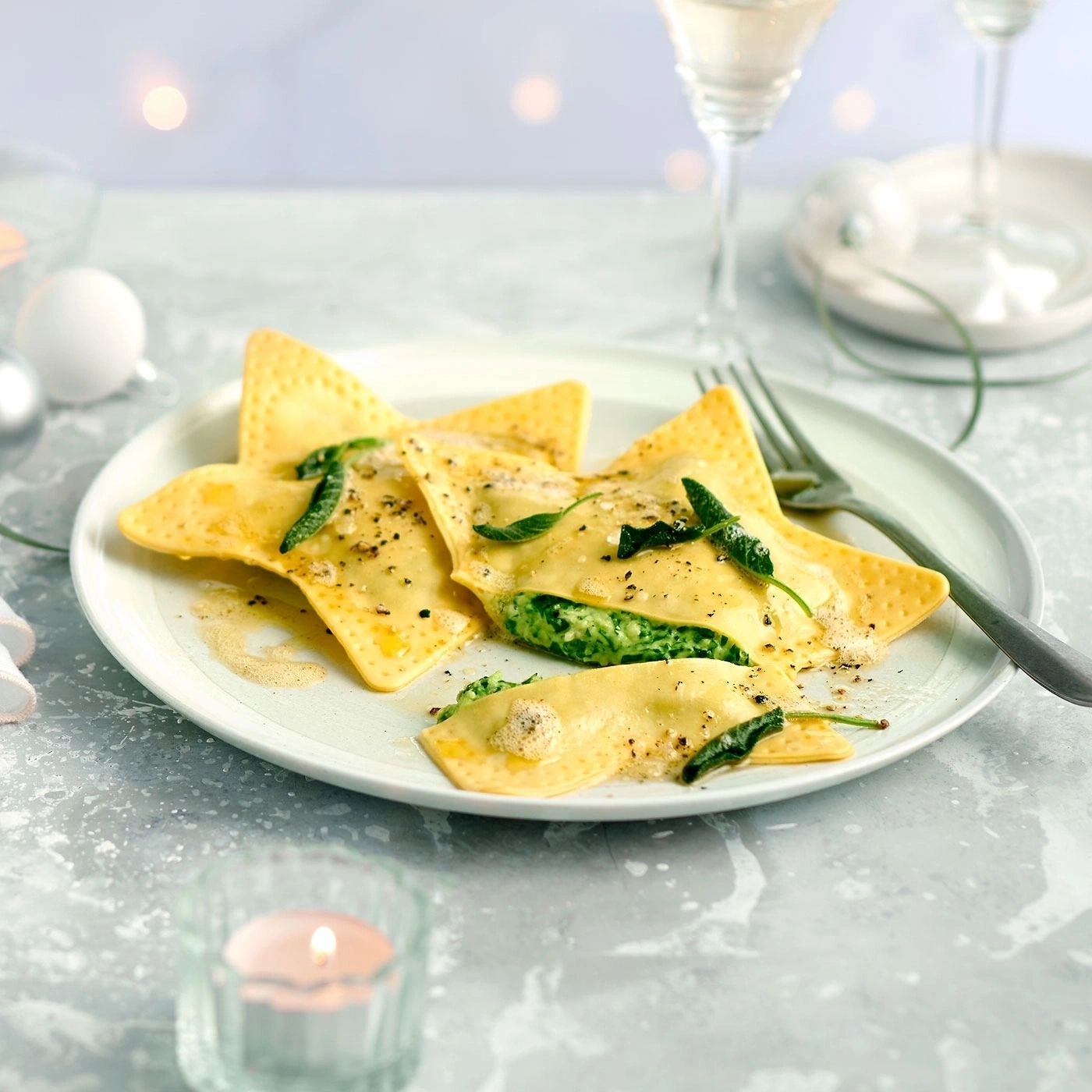 Sternförmige Ravioli mit Spinat auf einem Teller, serviert mit Wein.
