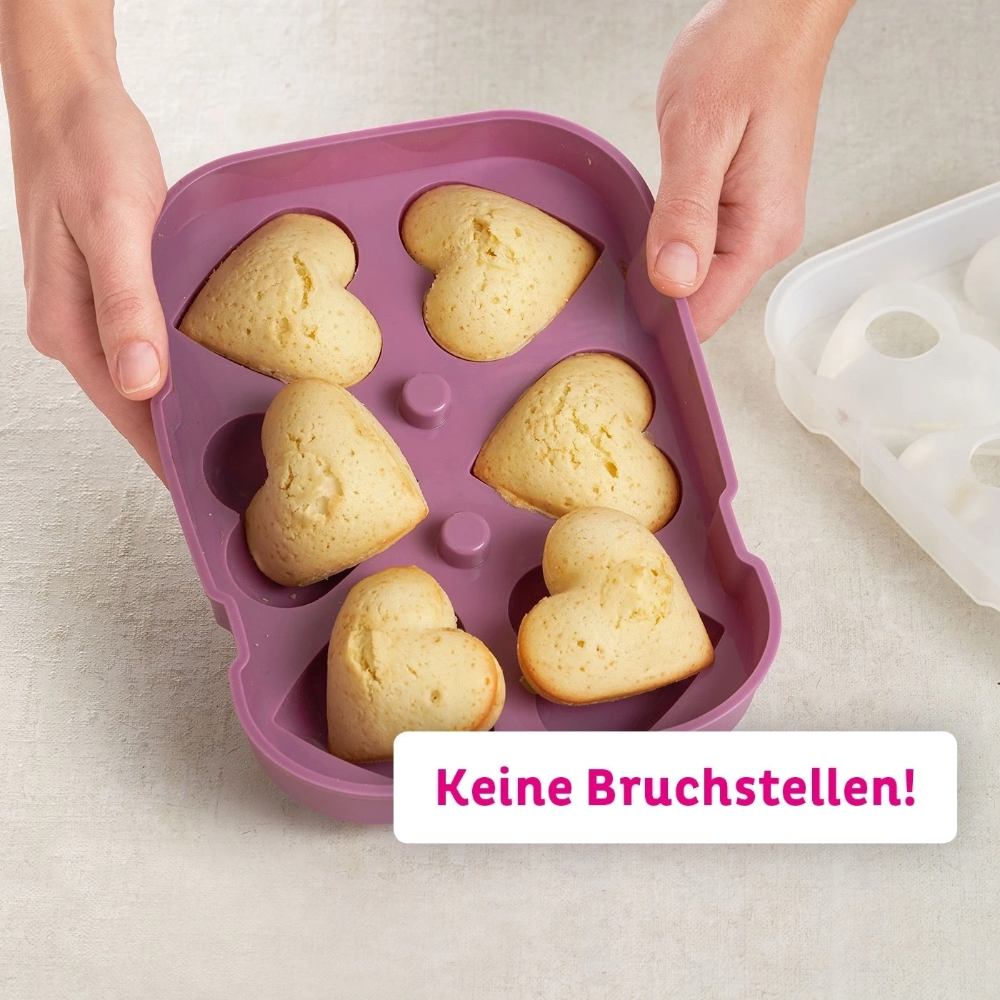 Person hält herzförmige Kuchen in einer Backform. Keine Bruchstellen!