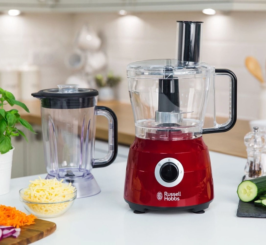 Küchenmaschine mit Zubehör, Käse und Gemüse auf einer Arbeitsplatte