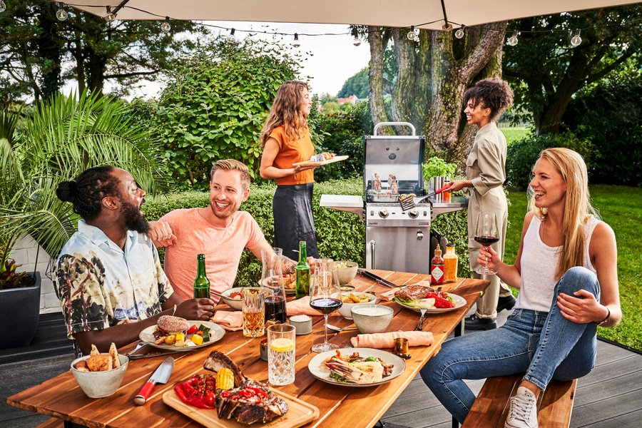 Freunde grillen im Garten, genießen Essen und Getränke, Sommerparty, fröhliche Stimmung