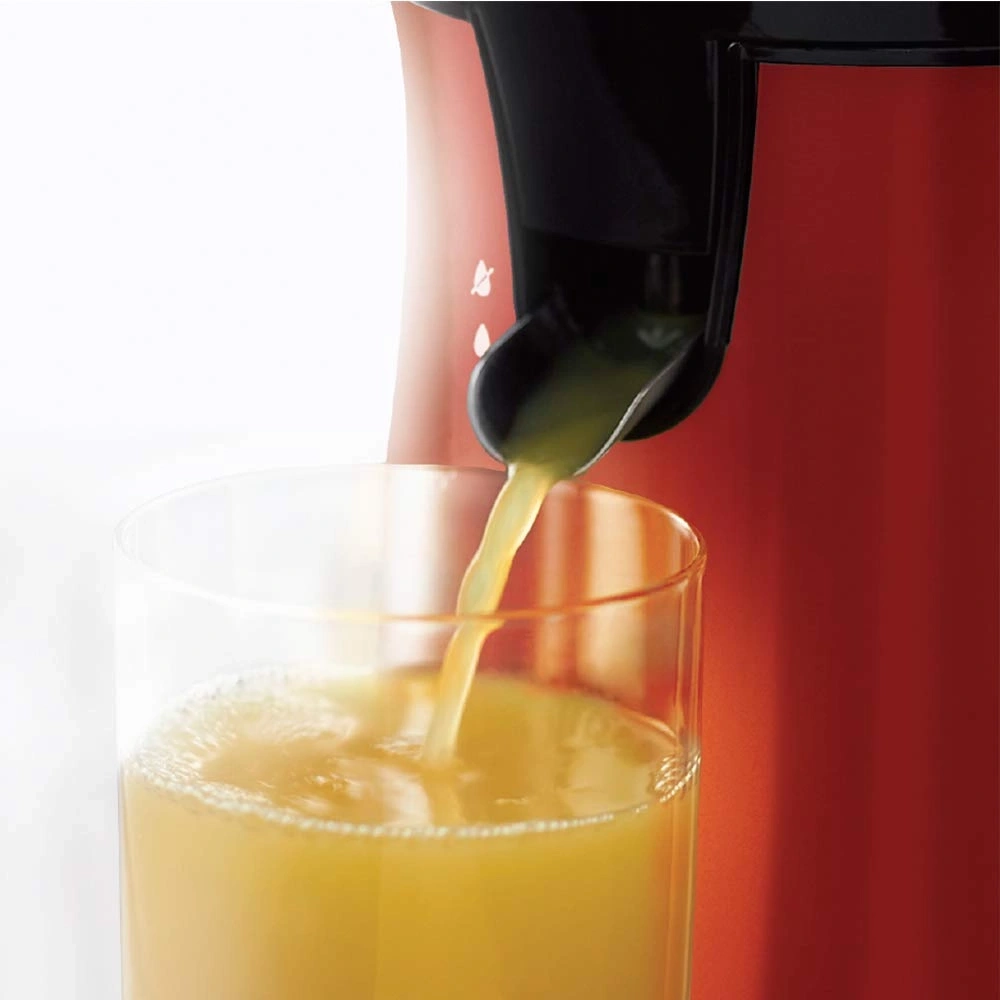 Nahaufnahme eines Saftes, der in ein Glas gegossen wird, mit einem roten Hintergrund