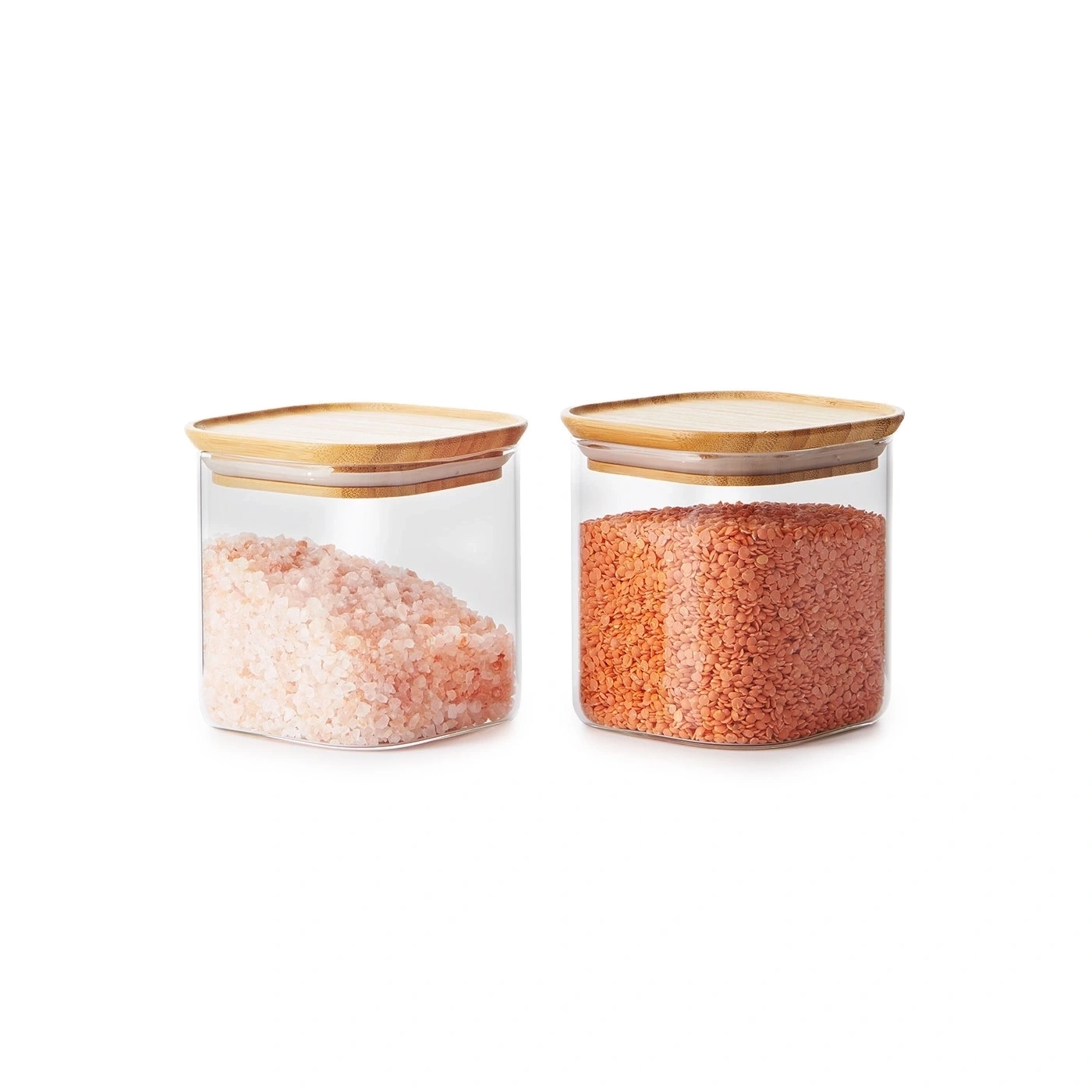 Zwei Glasbehälter mit Holzböden, einer gefüllt mit rosa Salz, der andere mit roten Linsen.