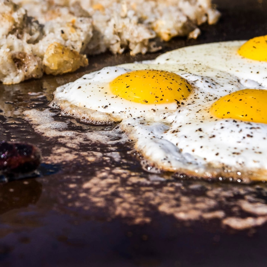 Gebratene Eier mit Hash Browns auf einer heißen Kochplatte, Frühstück