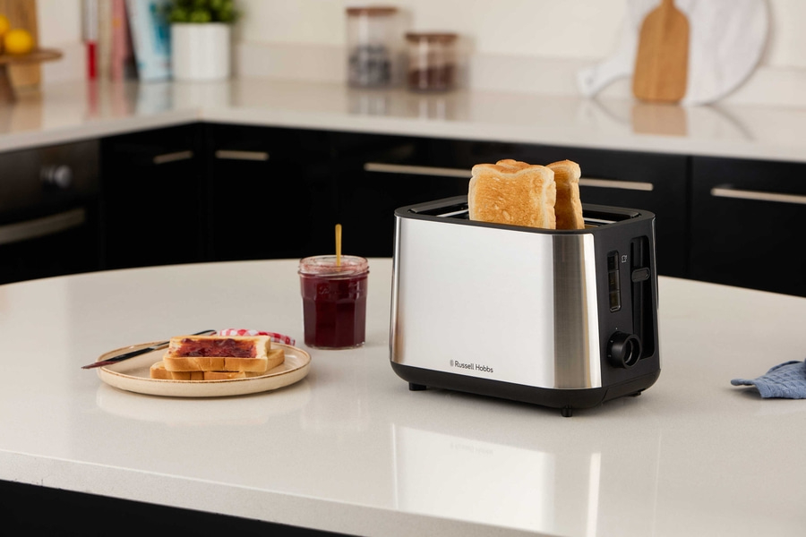 Ein Toaster mit Toast, Marmelade und Brot auf einem Teller auf einer Küchenarbeitsplatte.