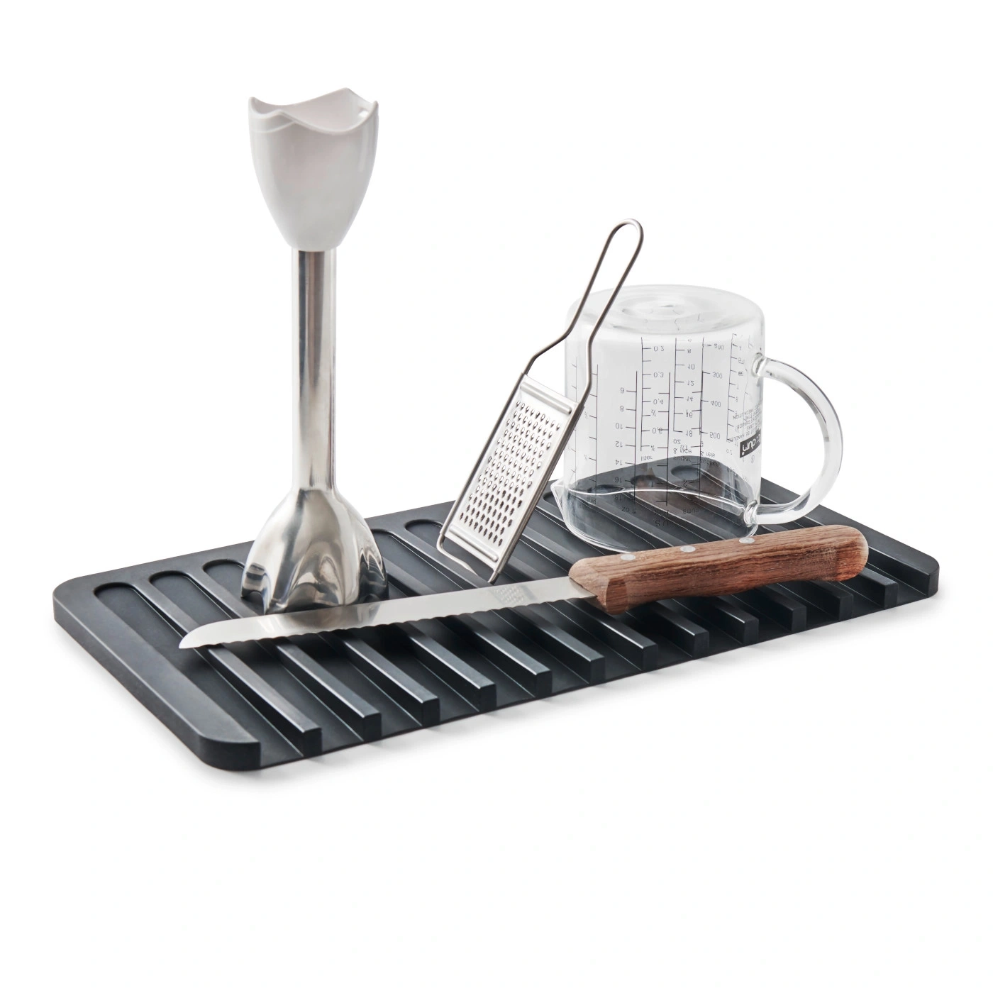 Küchenutensilien auf einer schwarzen Ablage: Stabmixer, Reibe, Messbecher, Messer.