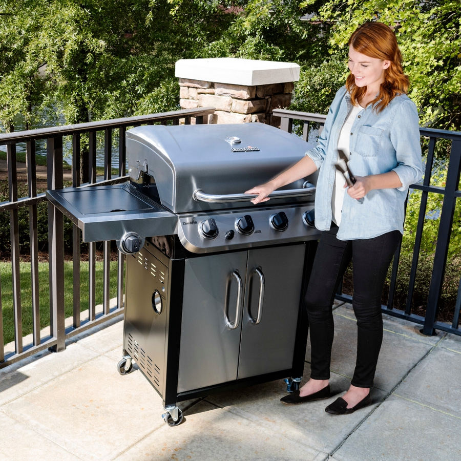 Frau am Grill im Freien, mit Grillzange, lächelnd, Sommer, Garten, Terrasse