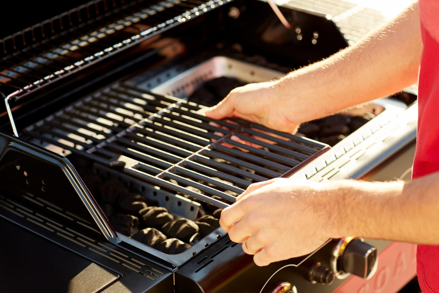 Person legt Grillrost in den Grill. Hände, Grill, Kohle, Sommer, Kochen.