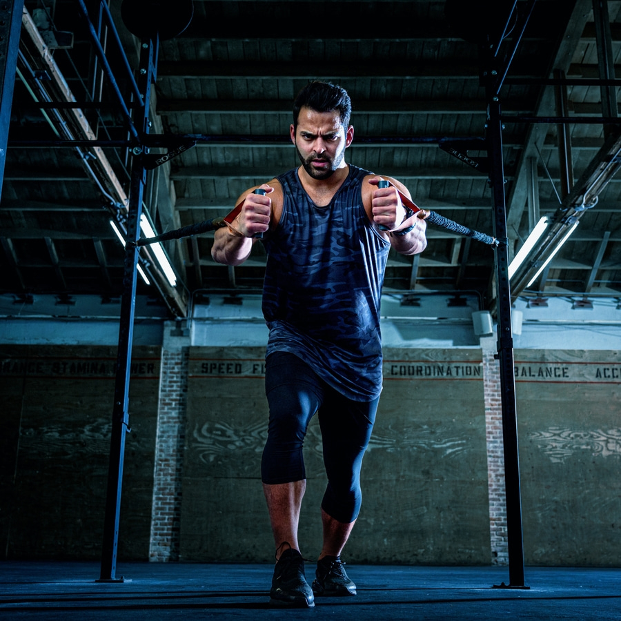 Mann trainiert mit Widerstandsbändern in einem Fitnessstudio. Er ist konzentriert und angespannt.