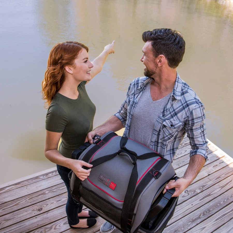 Paar am See mit Tasche, Frau zeigt auf etwas, Mann schaut.