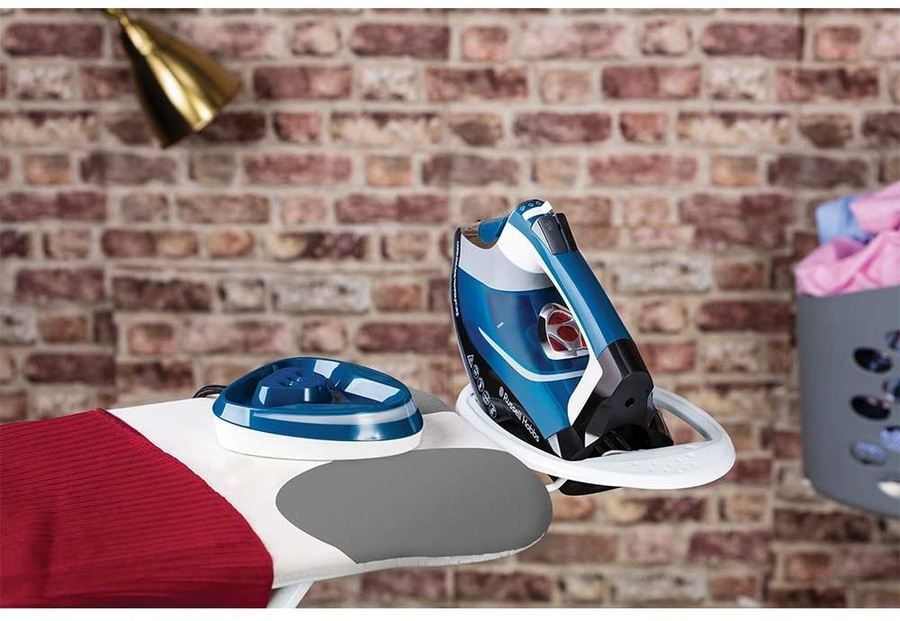 Bügeleisen auf Bügelbrett mit Zubehör vor Backsteinmauer